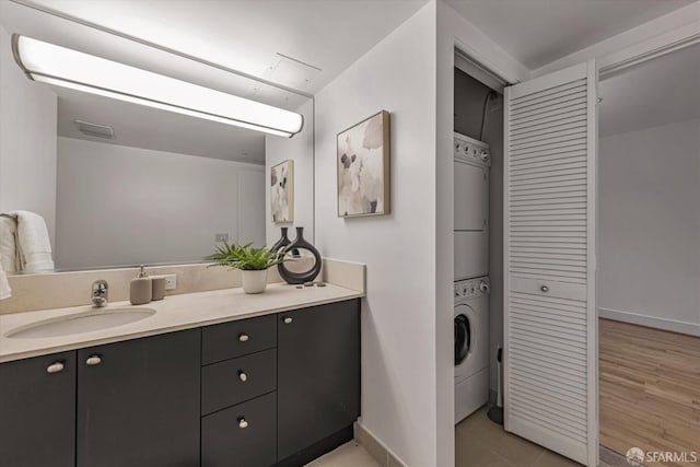 bathroom with tile patterned floors, vanity, and stacked washer and clothes dryer