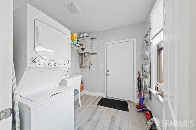 3000 26th St, San Francisco, CA 94110 - laundry room with stacked washer and clothes dryer, light wood-style floors, and baseboards