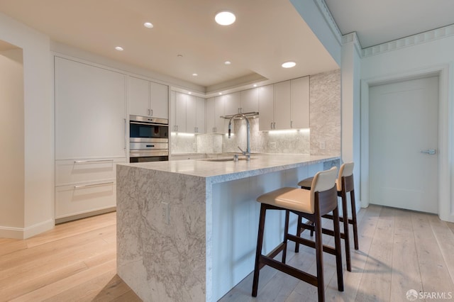 875 California St Unit 403, San Francisco, CA 94108 - kitchen with double oven, light wood-type flooring, decorative backsplash, and recessed lighting