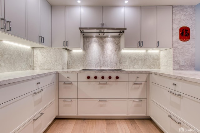 875 California St Unit 403, San Francisco, CA 94108 - kitchen with under cabinet range hood, light wood-style floors, white cabinets, light stone countertops, and backsplash