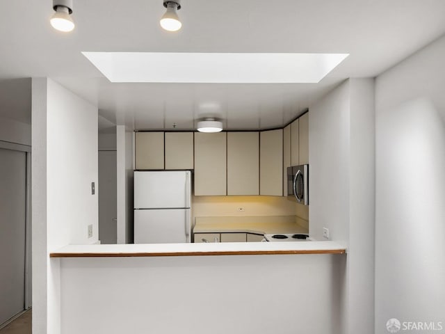 601 Van Ness Ave Unit 71, San Francisco, CA 94102 - kitchen with freestanding refrigerator, a skylight, stainless steel microwave, cream cabinets, and light countertops