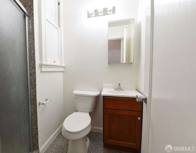 bathroom featuring toilet, a shower stall, vanity, and baseboards