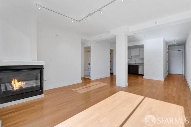 unfurnished living room featuring light hardwood / wood-style floors and rail lighting