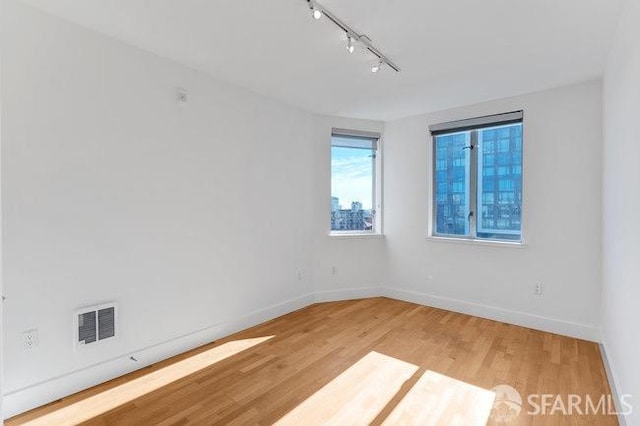 empty room featuring track lighting and hardwood / wood-style flooring