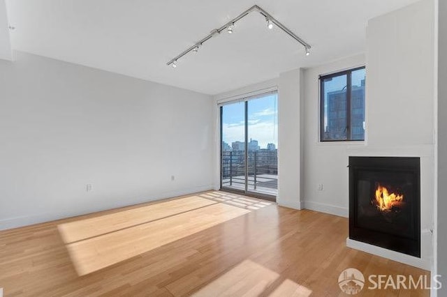 unfurnished living room with wood-type flooring and rail lighting