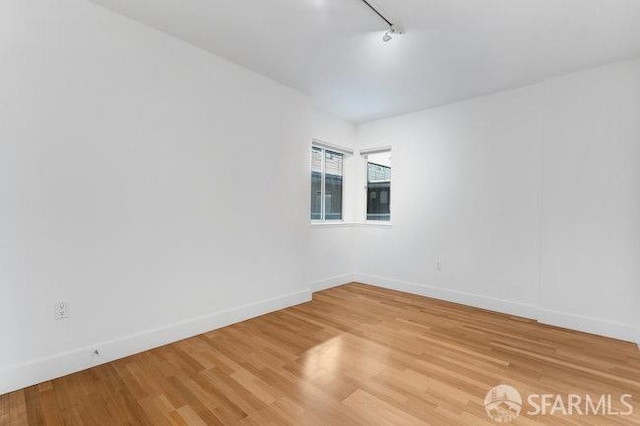 empty room featuring track lighting and hardwood / wood-style floors