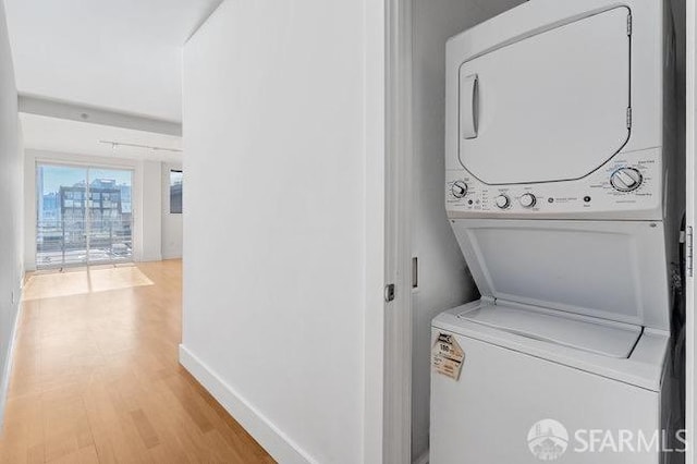 laundry area with light hardwood / wood-style floors and stacked washer / dryer