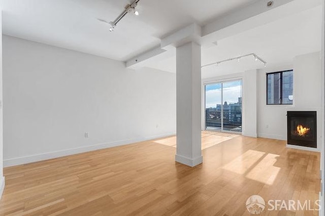 unfurnished living room with light hardwood / wood-style floors and track lighting