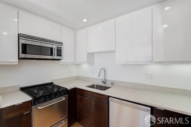 kitchen with dark brown cabinets, sink, stainless steel appliances, and white cabinets