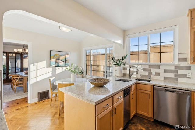 kitchen with sink, dishwasher, light stone counters, parquet flooring, and kitchen peninsula