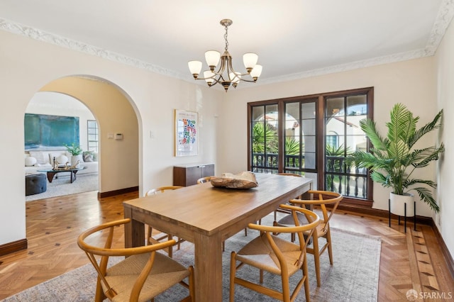 dining space with an inviting chandelier, light parquet flooring, and crown molding