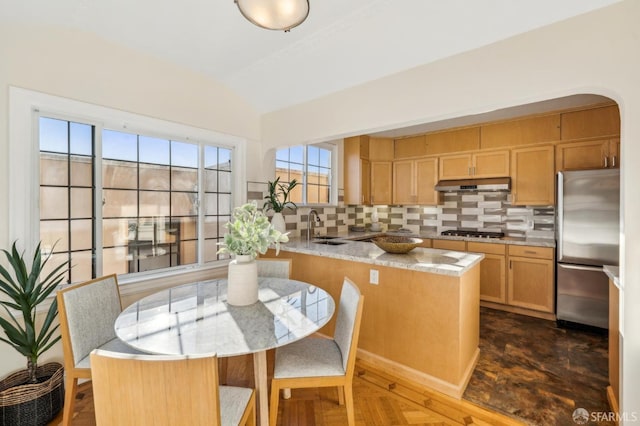 kitchen featuring sink, appliances with stainless steel finishes, tasteful backsplash, light stone countertops, and a kitchen island