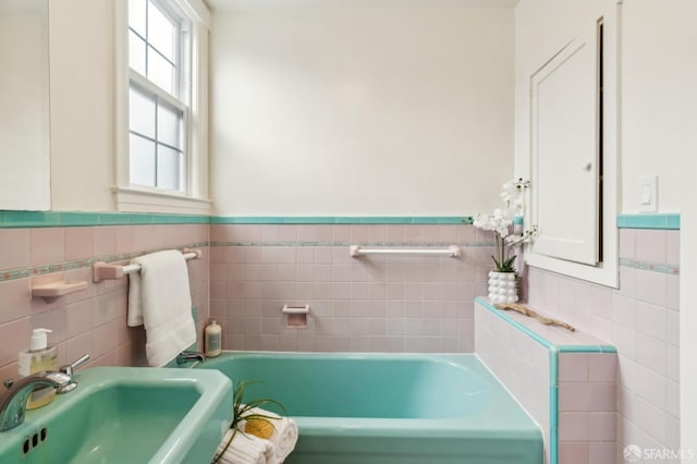 bathroom with tile walls, sink, and a healthy amount of sunlight