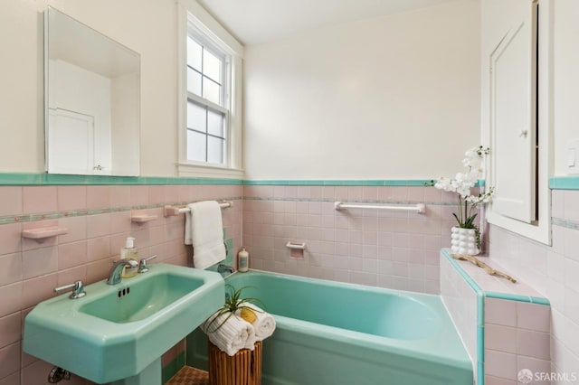 bathroom with sink, tile walls, and a tub to relax in