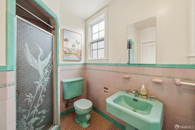 bathroom featuring a shower with door, tile patterned flooring, tile walls, and toilet