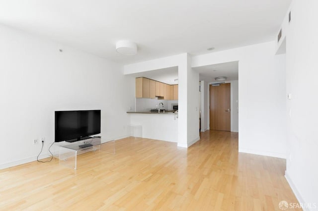 301 Mission St Unit 8E, San Francisco, CA 94105 - unfurnished living room with light wood-style floors, a sink, and baseboards