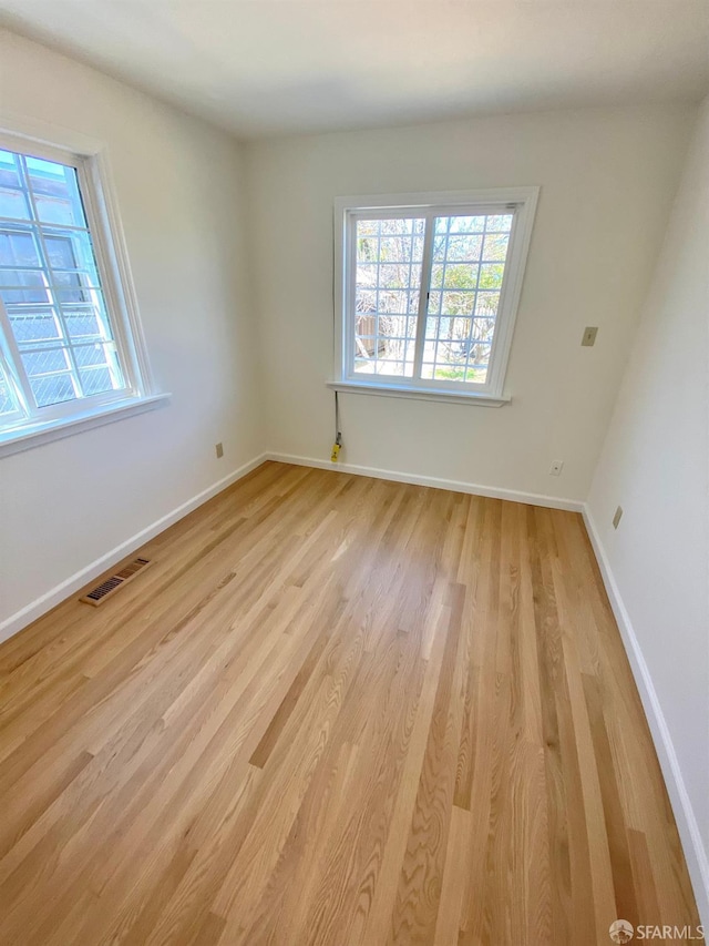 empty room with visible vents, baseboards, and light wood-style floors