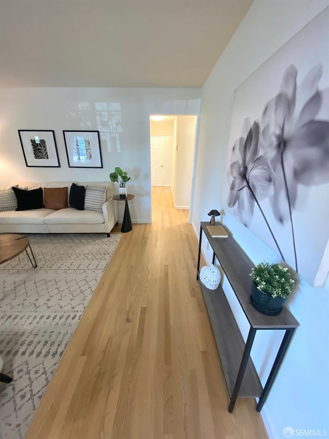 hallway featuring light wood-style flooring and baseboards