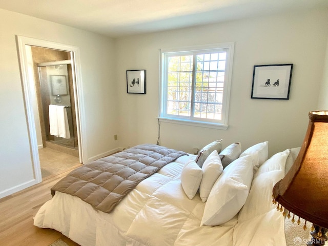 bedroom featuring ensuite bath, wood finished floors, and baseboards