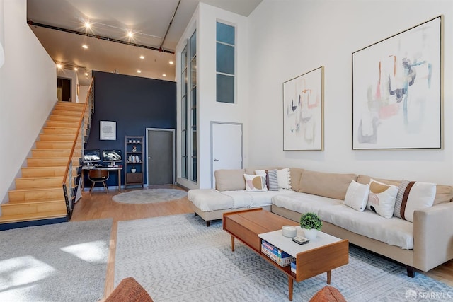 living room with a towering ceiling and light wood-type flooring