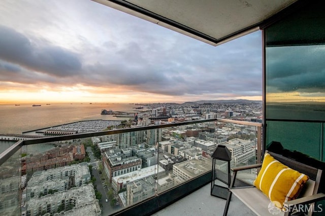 balcony at dusk featuring a water view