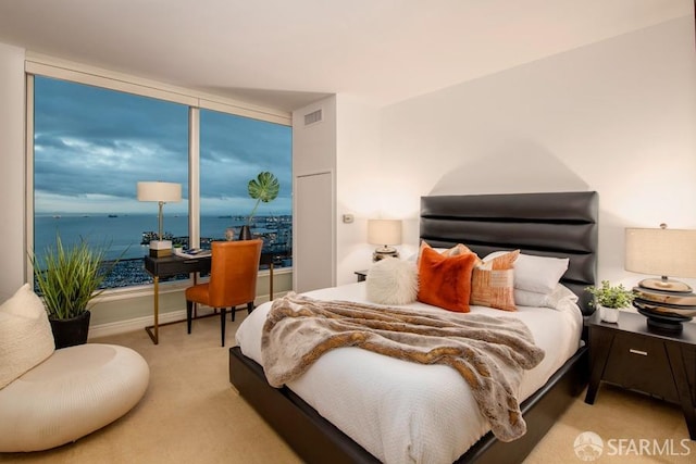 bedroom with light colored carpet and a water view