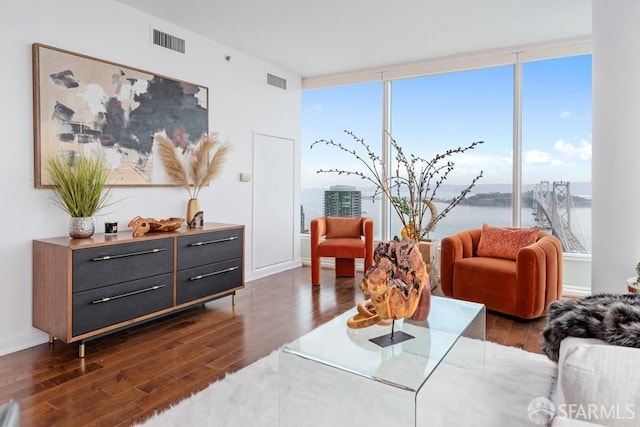 living room featuring a wealth of natural light, a water view, and dark wood-type flooring