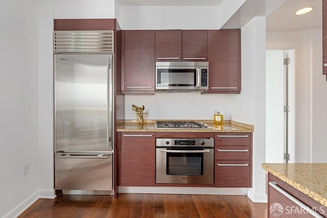 kitchen featuring light stone counters, dark hardwood / wood-style flooring, and stainless steel appliances