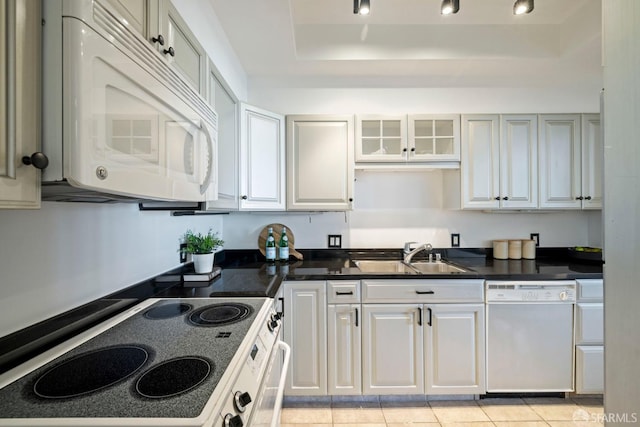 kitchen with white appliances, white cabinetry, light tile patterned floors, and sink