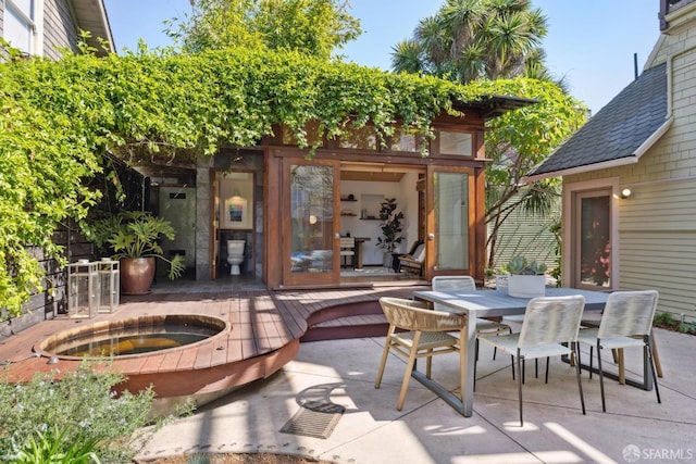 view of patio / terrace featuring outdoor dining space, an in ground hot tub, and an outbuilding