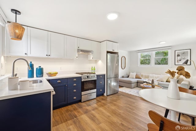 kitchen featuring blue cabinetry, a sink, open floor plan, appliances with stainless steel finishes, and light countertops