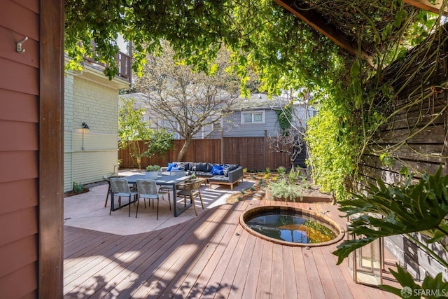 wooden terrace featuring a fenced backyard, an outdoor hangout area, and an outdoor hot tub