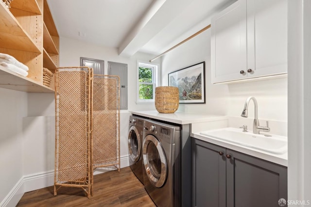 laundry room featuring baseboards, cabinet space, separate washer and dryer, dark wood-style flooring, and a sink