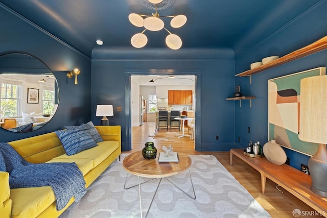 living room featuring a wealth of natural light, a chandelier, ornamental molding, and wood finished floors