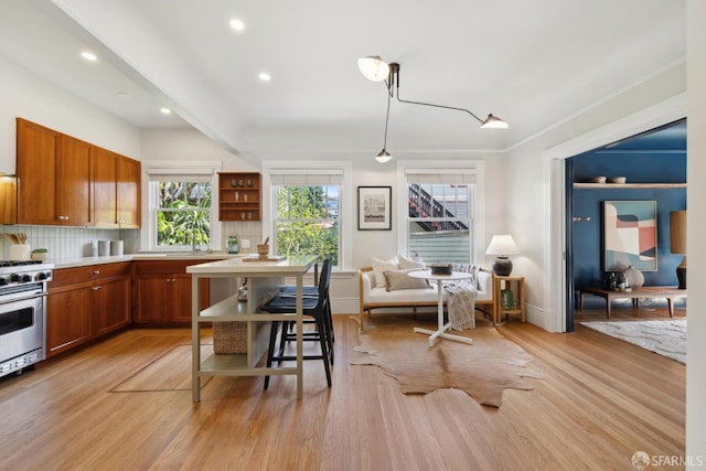 kitchen featuring stainless steel gas stove, brown cabinetry, and light wood finished floors