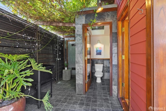 bathroom with a wainscoted wall, toilet, and tile walls