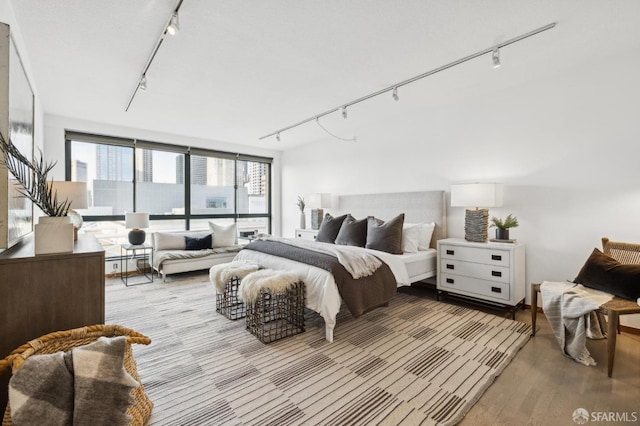 bedroom with track lighting and light wood-type flooring