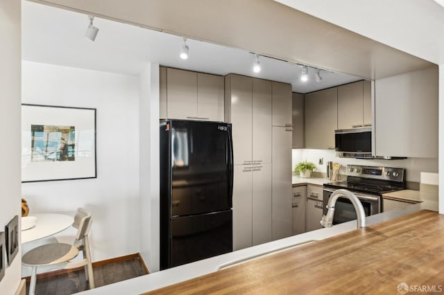 kitchen featuring track lighting, dark hardwood / wood-style floors, gray cabinets, appliances with stainless steel finishes, and kitchen peninsula