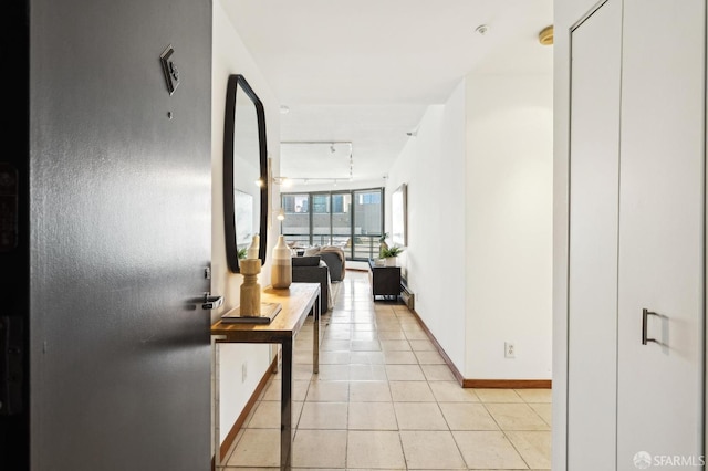 hall featuring floor to ceiling windows, light tile patterned floors, and track lighting