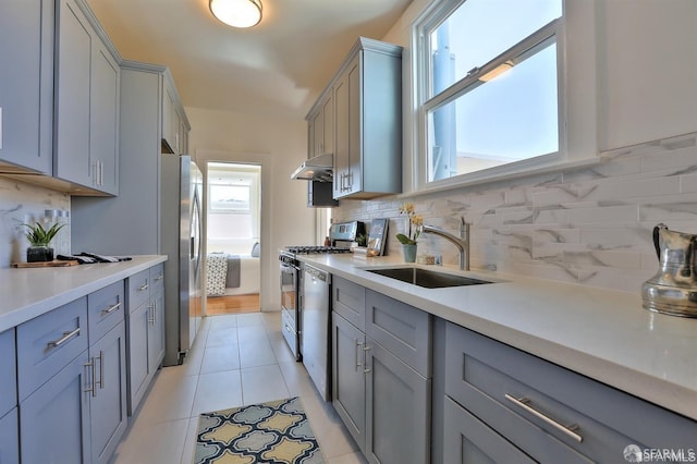 kitchen with appliances with stainless steel finishes, sink, light tile patterned floors, and gray cabinets