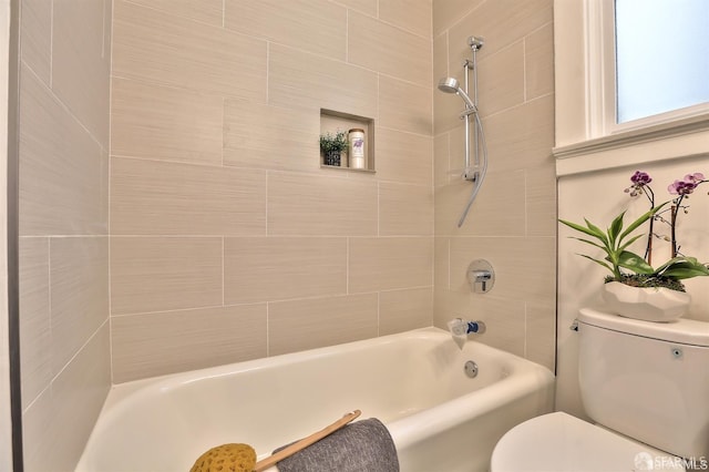 bathroom with tiled shower / bath combo and toilet