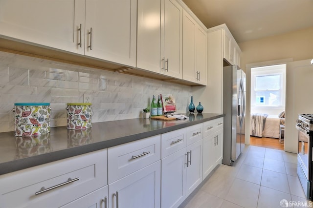 kitchen with decorative backsplash, white cabinets, appliances with stainless steel finishes, and light tile patterned flooring