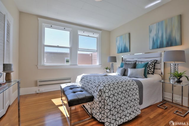 bedroom with baseboard heating and hardwood / wood-style flooring