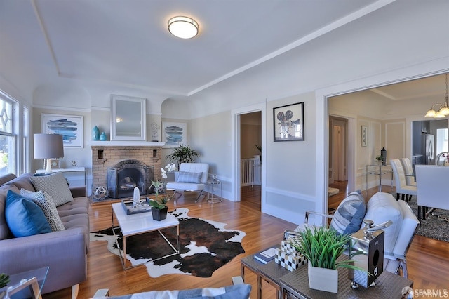 living room featuring a brick fireplace, an inviting chandelier, and hardwood / wood-style floors