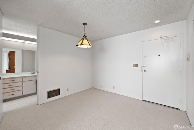 unfurnished dining area with light carpet and a textured ceiling