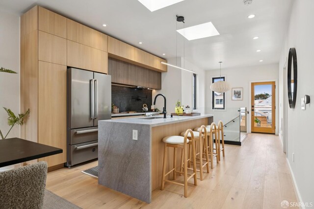 738 Athens St, San Francisco, CA 94112 - kitchen with high end refrigerator, light wood-style flooring, modern cabinets, a skylight, and a breakfast bar