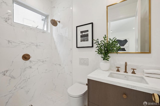 bathroom with a tile shower, toilet, and vanity