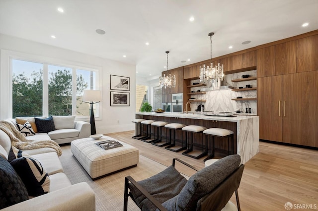 living room with sink, a chandelier, and light hardwood / wood-style floors