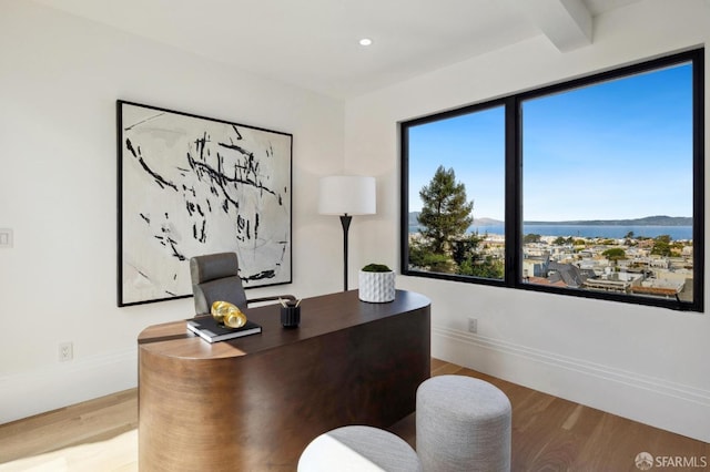 home office with beam ceiling, a water view, and hardwood / wood-style floors