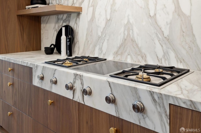 details with light stone countertops, stainless steel gas stovetop, and tasteful backsplash